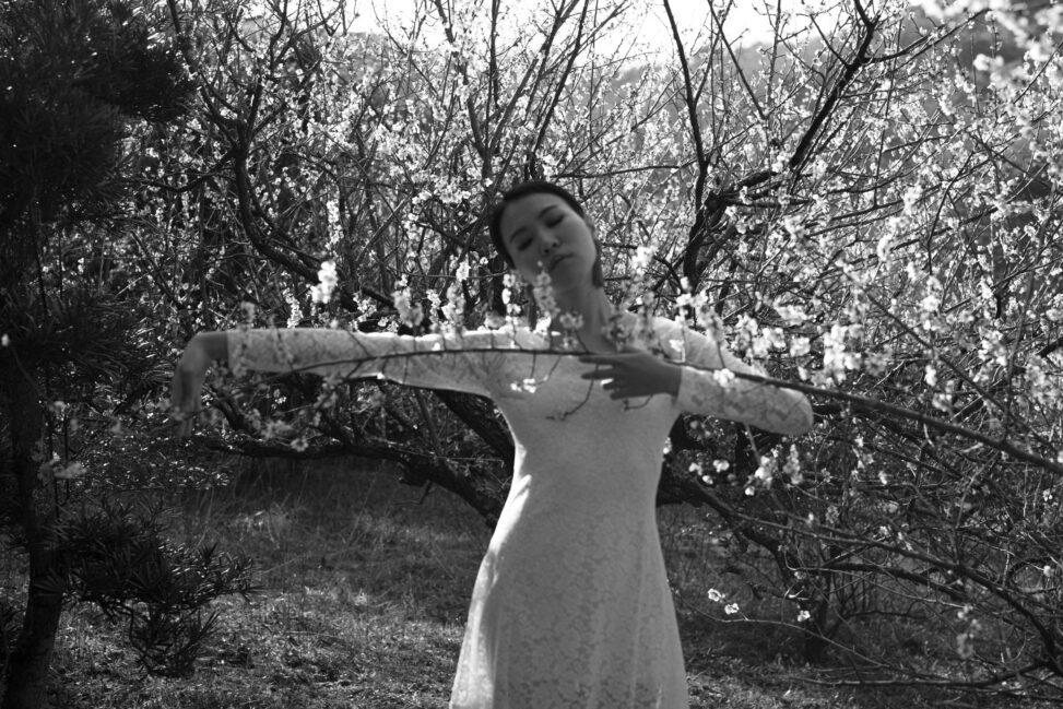 ayaをモデルに、和田剛が撮影したポートレート作品「somewhere」。季節の花とモデルを撮影したモノクロームの人物写真。